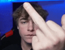 a young man is making a middle finger gesture .