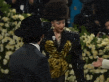 a man in a hat is talking to a woman in a yellow and black dress