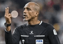 a referee is wearing a black shirt that says fifa