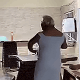 a woman in a blue dress is standing in a kitchen with her back to the camera .