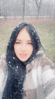 a woman in a plaid jacket stands in the snow