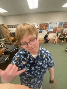 a boy wearing glasses and a hawaiian shirt is pointing