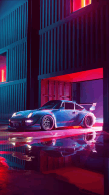 a blue sports car is parked in front of a building at night