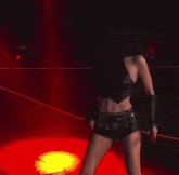 a woman is singing into a microphone on a stage with red lights behind her .