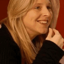 a close up of a woman 's face with blonde hair wearing a black sweater .