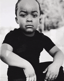 a black and white photo of a young boy in a black t-shirt