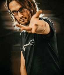 a man wearing glasses and a black shirt with a horse on it is making a peace sign