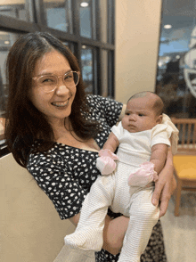 a woman is holding a baby in her arms and smiling