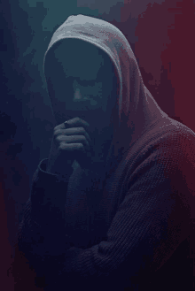 a man in a hooded sweater with his hands on his face