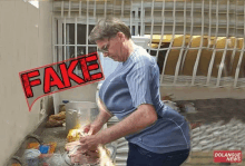 a man in a blue shirt is washing a chicken in a kitchen with a fake sign above him