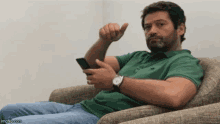 a man is sitting in a chair holding a cell phone in his hand .