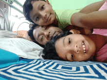 a man and two children laying on a bed with a striped blanket