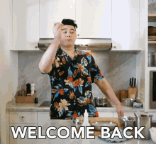 a man in a floral shirt is standing in a kitchen with the words welcome back written on the counter