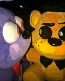 a purple stuffed animal and a yellow stuffed animal are standing next to each other