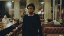 a man wearing a black sweater is standing in a diner