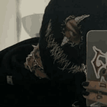 a person wearing a black ski mask is taking a selfie with a cell phone .