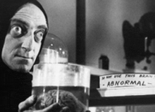 a black and white photo of a man holding a jar of brains