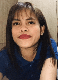 a woman wearing a blue shirt and red lipstick is smiling