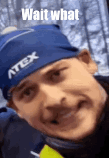 a man wearing a blue hat with the word atex on it is smiling .