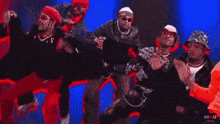 a group of men are dancing in front of a red and blue background with the letters nm on the bottom right