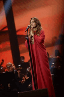 a woman in a red dress is singing into a microphone on stage