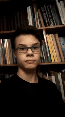 a young man giving a thumbs up in front of a shelf of books including one titled wilde / ida vans