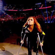 a woman with red hair is standing in front of a crowd in a stadium while holding a microphone .