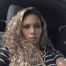 a woman is sitting in the back seat of a car and says i love u .