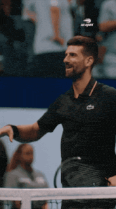 a man holding a tennis racquet and wearing a black shirt that says us open