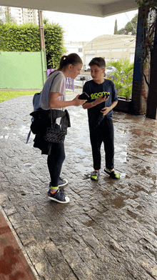 a boy wearing a shirt that says sports on it talks to a girl