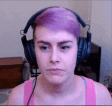 a woman with purple hair wearing headphones and a pink tank top .