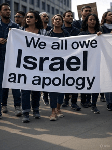 a group of people marching with a banner that says we all owe israel an apology