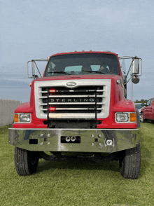 a red sterling truck is parked on a lush green field