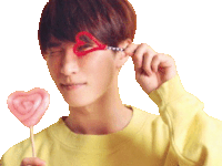 a young man wearing a pair of heart shaped glasses and holding a pink heart shaped lollipop