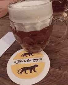 a glass of beer is sitting on top of a coaster with a leopard on it .