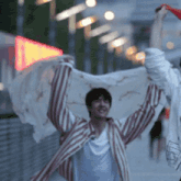 a man in a red and white striped shirt is holding a white cloth in his hands