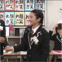 a girl in a school uniform shakes hands with another girl in front of a green board with chinese writing on it