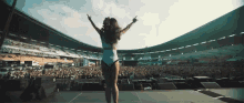 a woman in a bathing suit stands on a stage in front of a crowd at a stadium that has the word stadium on it