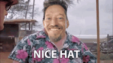 a man with a beard wearing a floral shirt says nice hat