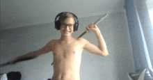 a shirtless boy wearing headphones holds a sword over his shoulder