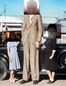 a very tall man in a suit stands next to two small girls