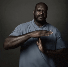 a man wearing a blue polo shirt holds his hands together