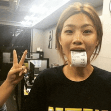 a woman is holding a receipt in her mouth and making a peace sign