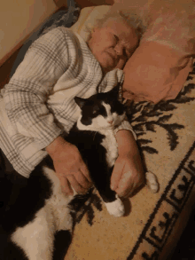 an elderly woman is laying on a bed with a black and white cat on her lap