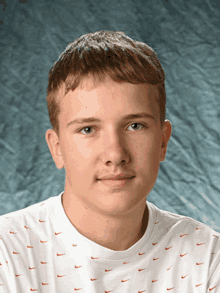 a young man wearing a white nike t-shirt looks at the camera