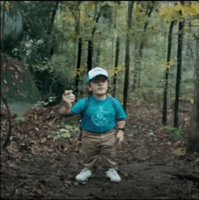 a little boy wearing a blue shirt with a compass on it is in the woods