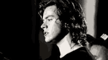 a black and white photo of harry styles with long curly hair .