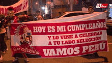 a man holding a banner that says hoy es mi cumpleanos y lo vine a celebrar a tu lado seleccion vamos peru