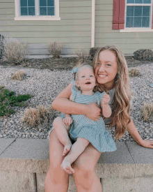 a woman is holding a baby in her arms and smiling