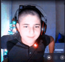 a young boy wearing headphones looks at the camera in front of a christmas tree